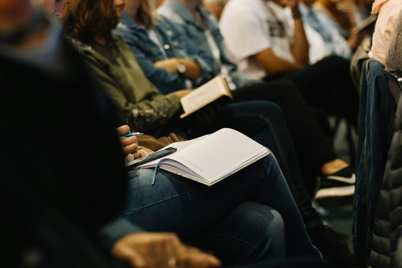People in a meeting with notebooks on their laps. Photo by Sincerely Media on Unsplash.